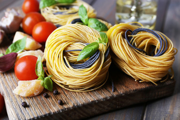 Raw pasta with cheese and vegetables on wooden background
