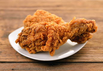 fried chicken on a white plate set on a wood