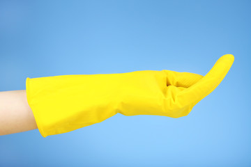 Rubber glove on hand, on blue background