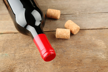 Glass bottle of wine with corks on wooden table background