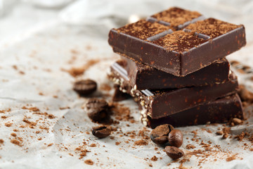 Pieces of chocolate with cocoa on parchment, closeup