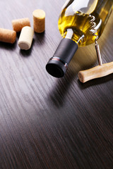 Bottle of wine with corks and corkscrew on wooden background