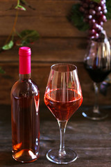 Bottle and glasses of wine with grape on wooden background