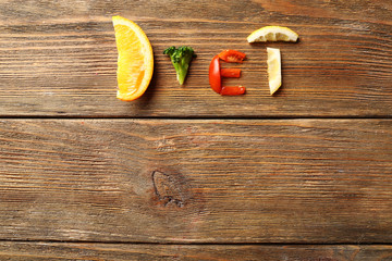 Word DIET made of sliced vegetables on wooden background