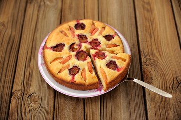 Plum and apple pie, cut, on wooden background