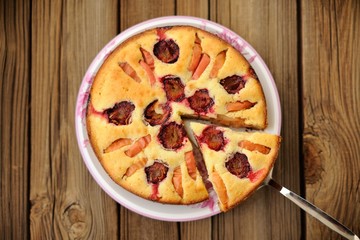 Plum and apple pie, cut, on wooden background