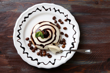 Tasty panna cotta dessert on plate, on wooden table