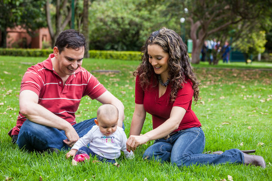 Pareja joven disfrutando de un hermoso d&iacute;a de sol con su bebita en un parque