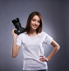 Young female photographer taking photos on grey background