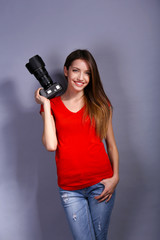 Young female photographer taking photos on grey background