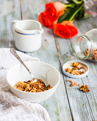 granola with honey, nuts and dried fruits in white piala, flower