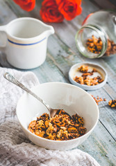 granola with honey, nuts and dried fruits in white piala, flower