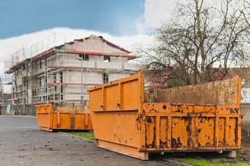 Fototapeta premium Grosse orange Container stehen vor einem Rohbau