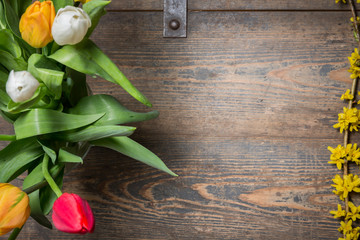 Tulips in an vase and flowers on a wooden chest
