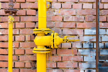 Yellow gas pipe and valve on red brick wall, copyspace