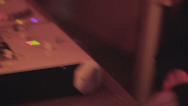 DJ working at nightclub, hands tweak controls on record deck