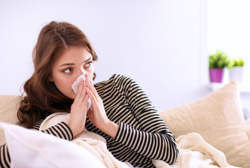 Portrait of a sick woman blowing her nose while sitting on the