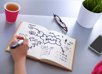 Young woman writes to diary on a white table