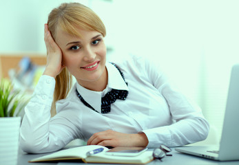 Fototapeta premium Portrait of businesswoman sitting at desk with a laptop