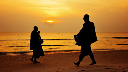 Silhouette of monk walk on the beach with beutuful