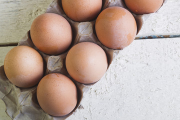 Eggs in a cardboard tray on a white boards.