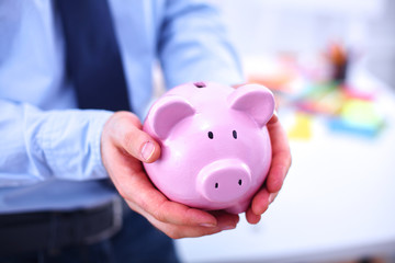 Businessman holding piggy box ,standing in office