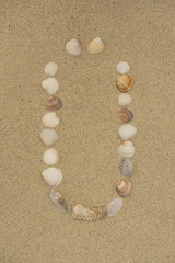 Buchstabe Ü aus Muscheln im Sand