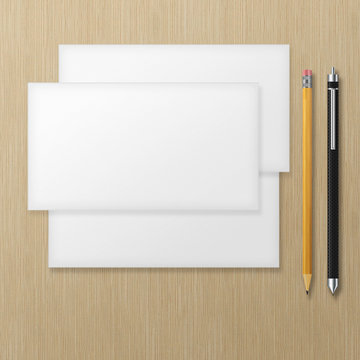 Set of blank envelopes with yellow pencil and pen on wooden back