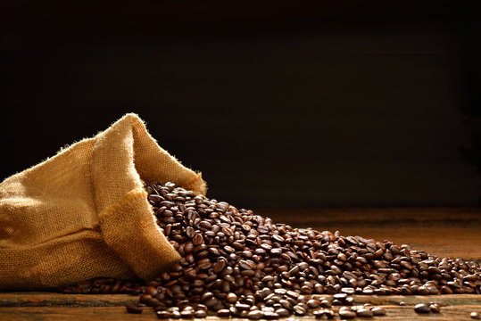 Coffee beans in burlap sack on wooden table