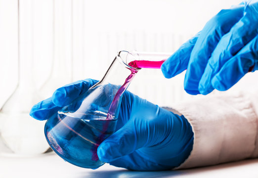 assistant reagent pouring into the flask