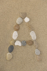 Fototapeta na wymiar Buchstabe A aus Kieselsteinen im Sand