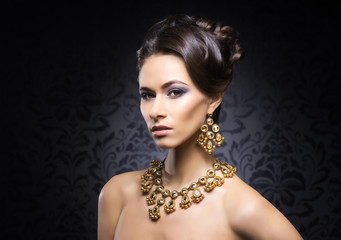 Young, beautiful and rich woman in jewels of gold