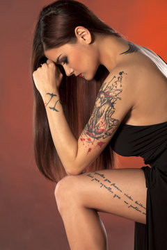 pretty young woman with tattoos posing in a black dress