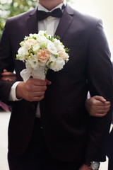 Beautiful wedding bouquet in hands of the groom. Gift to the bri