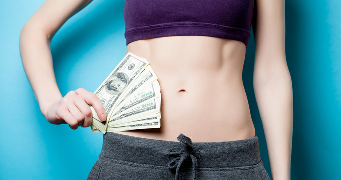 Woman showing her abs with dollars after weight loss