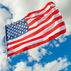 Neat USA flag with cumulus clouds on background - outdoors shot