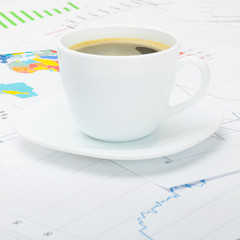 Coffee cup over financial chart - close up studio shot