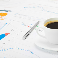 Coffee cup and calculator over some financial chart