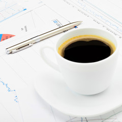 Coffee cup and calculator over some financial charts