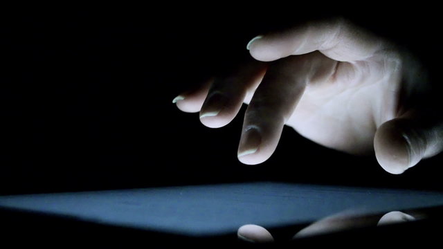 Woman touching tablet touch screen at dark