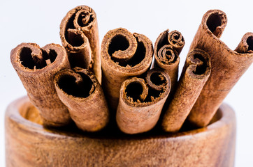 Obraz na płótnie Canvas close up of cinnamon stick on wooden bowl isolated on white