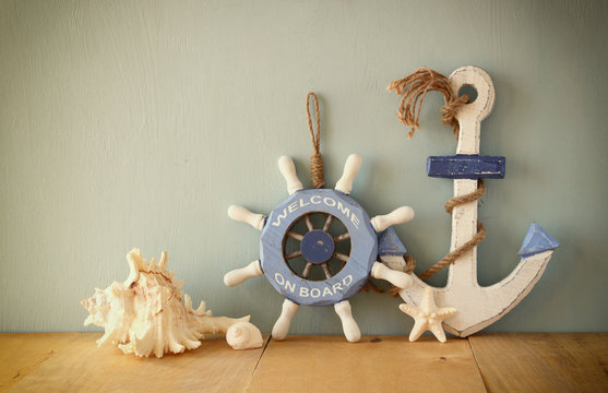 old nautical wood wheel, anchor and shells on wooden table over 