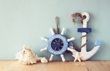 old nautical wood wheel, anchor and shells on wooden table over  © tomertu