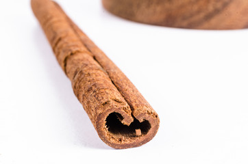 close up of cinnamon stick on wooden bowl isolated on white