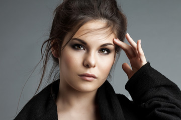 Woman in black coat with flying locks looking at the camera