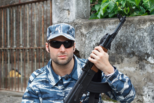 Portrait of military caucasian man in urban warfare holding rifl