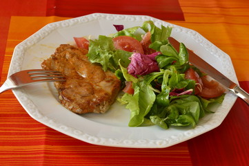 Pork steak and fresh salad on a white plate