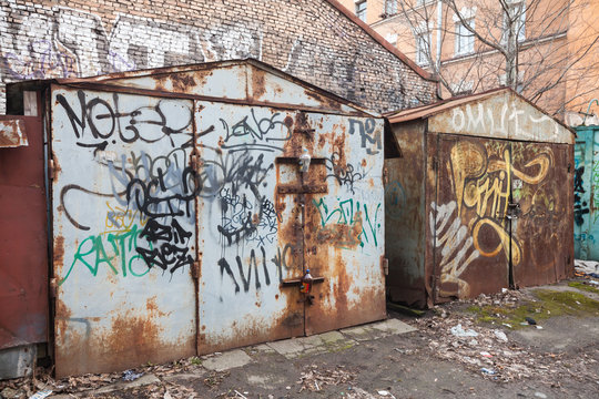 Two old rusted locked garages with grungy graffiti