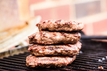 Pile of grilled ground beef patties on BBQ