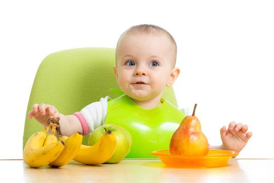 baby sitting at table with fruits